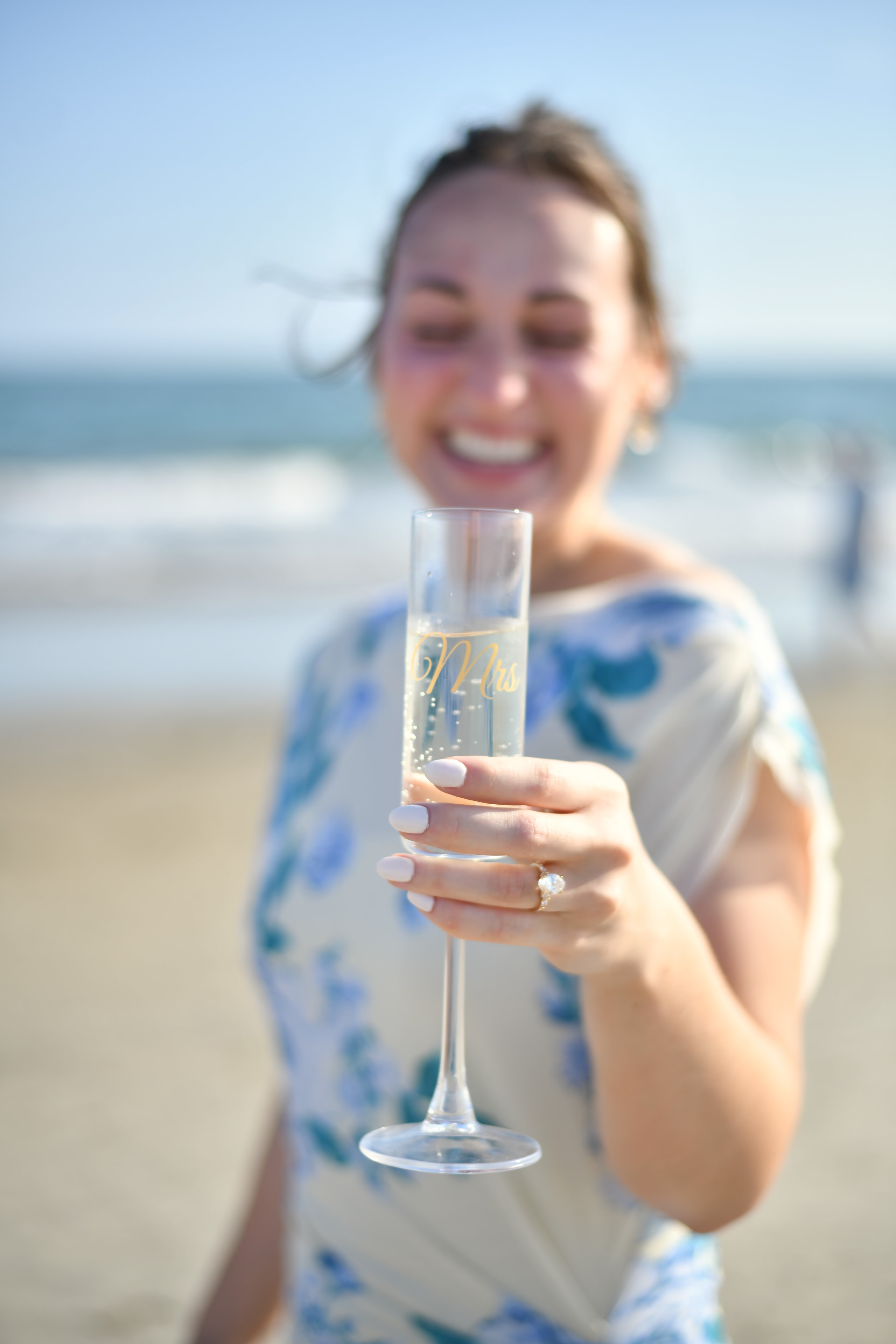 Bride holding a champagne flute on the beach