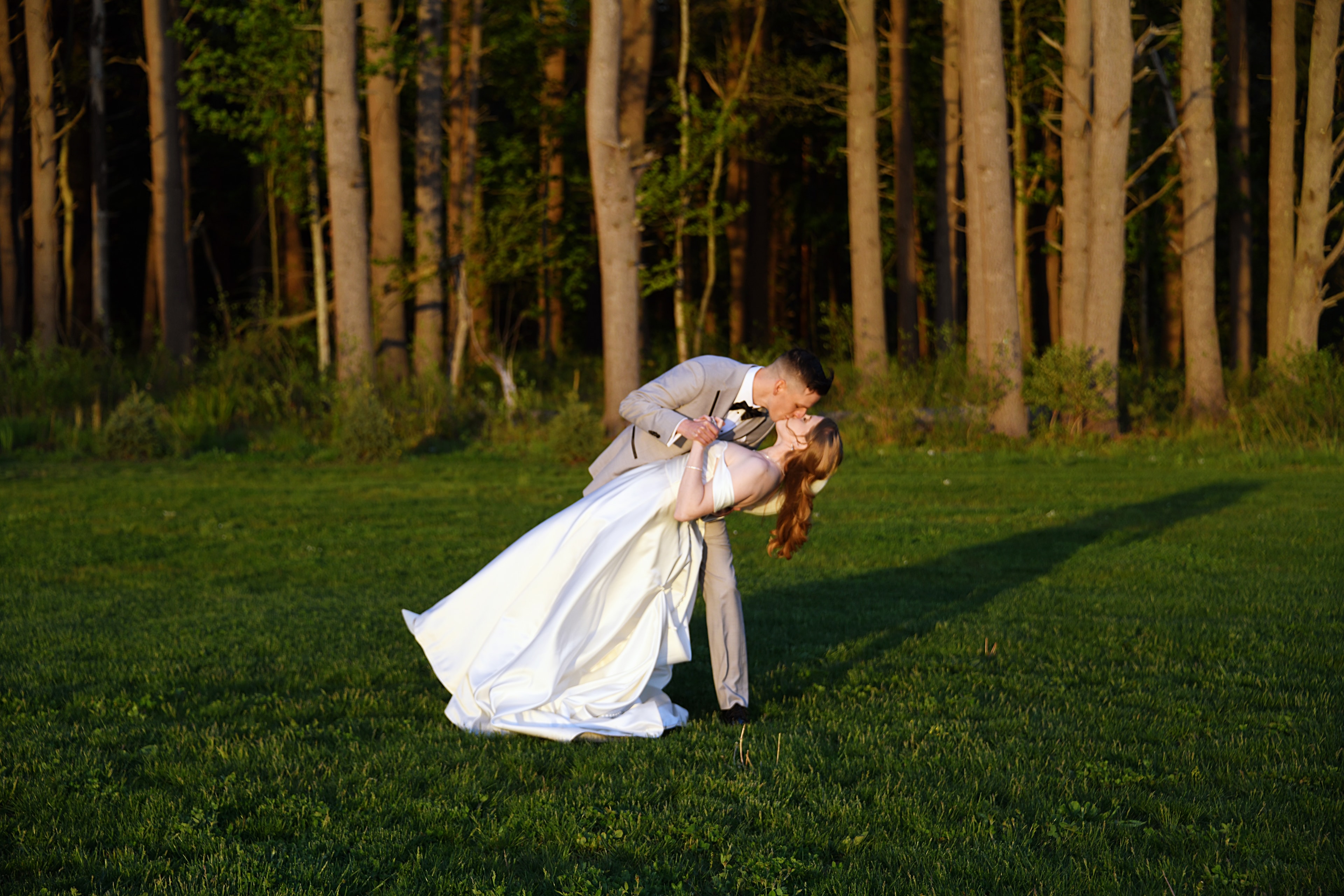 Groom dipping bride in a romantic kiss outdoors
