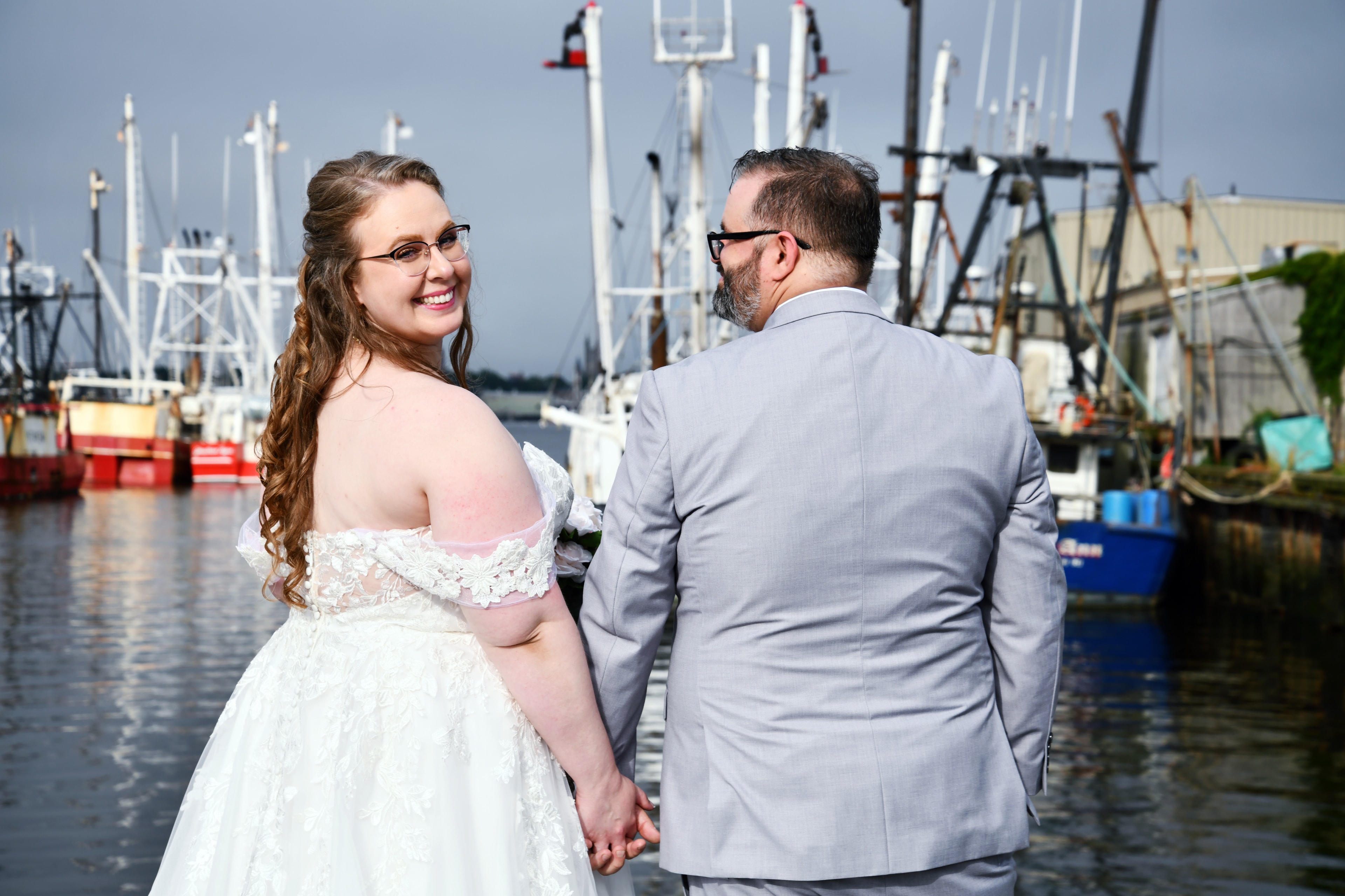 Bride looking back at groom at marina